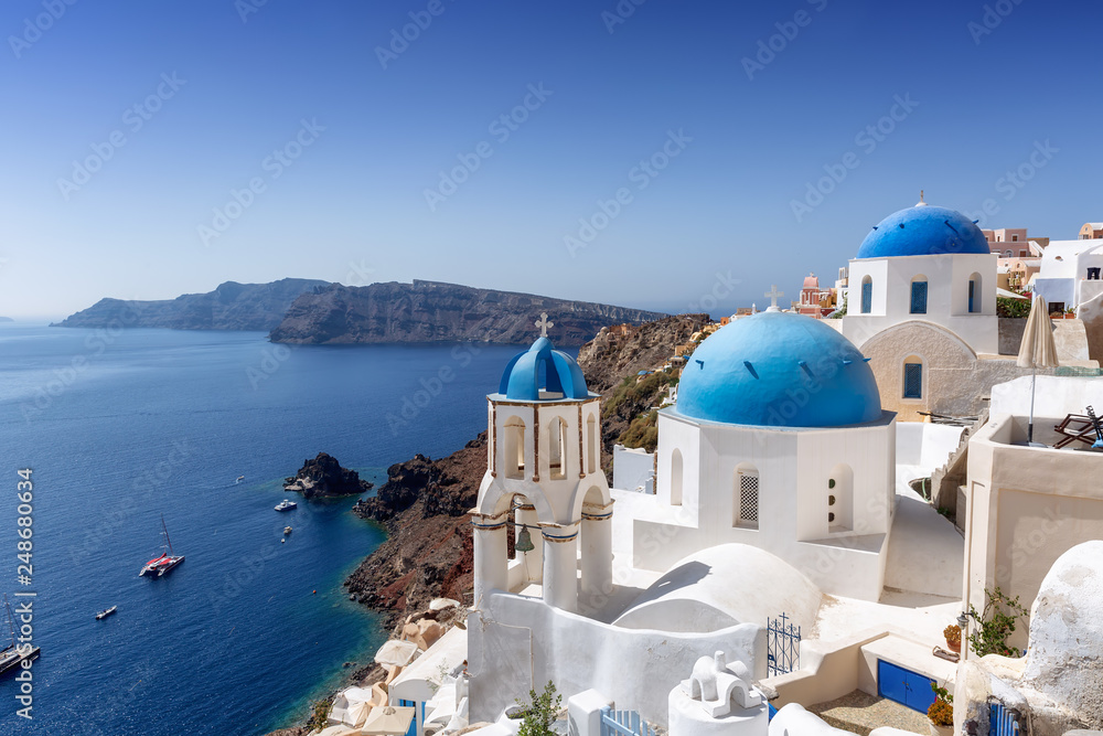 Fototapeta premium Niebieskie kopuły kościołów w Oia na skraju krateru wulkanu na Santorini, Cyklady, Grecja