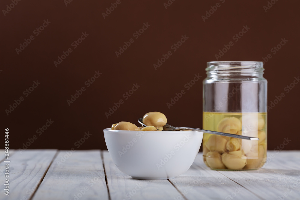 mushrooms in oil in ceramic bowl on white wooden background. mushrooms in oil in ceramic bowl on white wooden background.