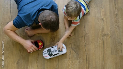 Family concept. Boy and dad playing with cars on wooden floor. Father with son. Directly above view