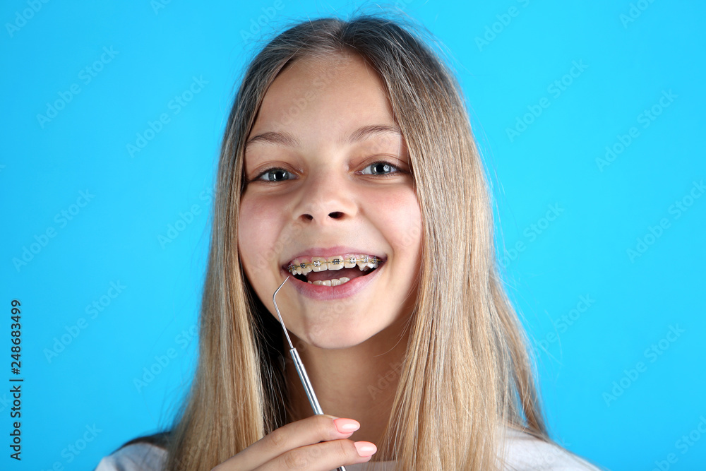 Young smiling girl with dental braces and toothbrush on blue background Young smiling girl with dental braces and toothbrush on blue background