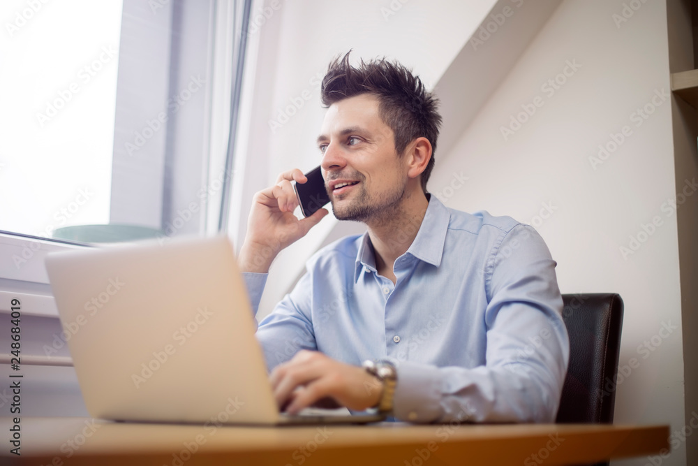 Young businessman using mobile phone and working on laptop Young businessman using mobile phone and working on laptop