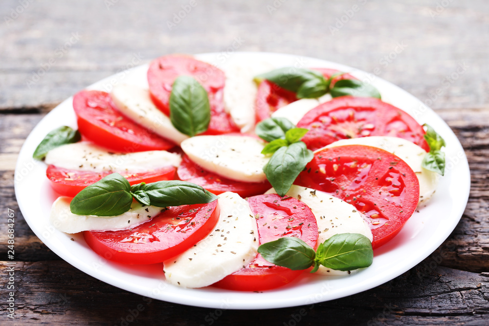 Mozzarella, tomatoes and basil leafs on grey wooden table Mozzarella, tomatoes and basil leafs on grey wooden table