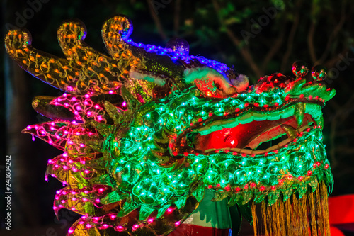 Chinese New Year Dragon Lights with Bokeh Background. Closeup of colorful dragon on night black background (soft blur with poor light and noise grain) during Chinese New Year festival.