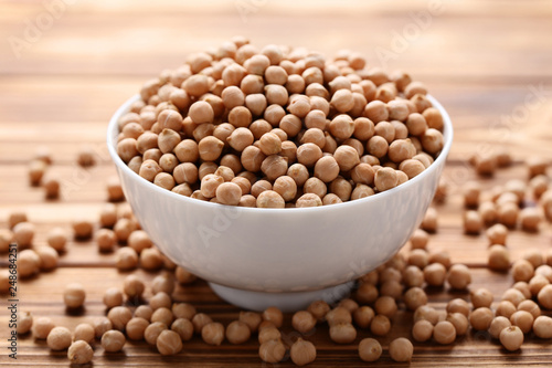 Chickpeas in white bowl on brown wooden table