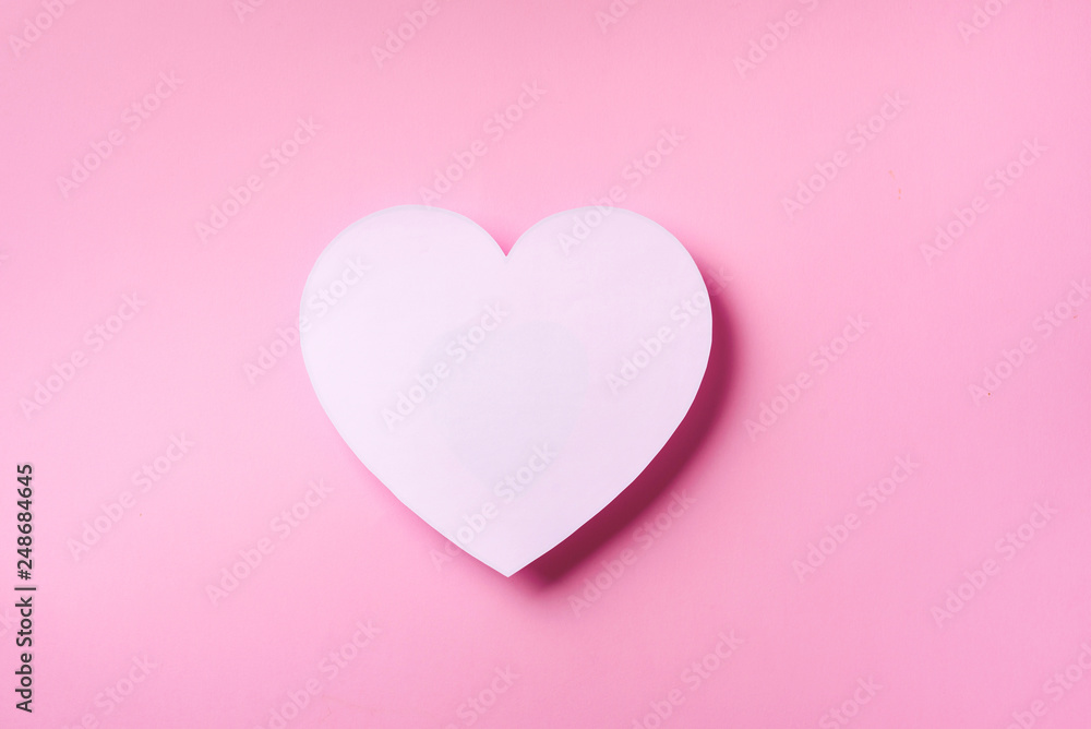White heart cutted from paper over pink punchy pastel background with copy space. Top view. Valentine's Day. Love, date, romantic concept.