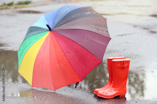 Red rubber boots with umbrella in puddle after rain © 5second