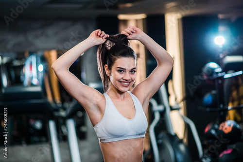 Young woman getting ready for fitness training, tying her hair and looking at camera.
