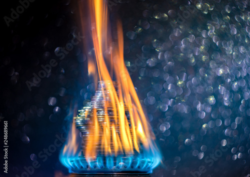 Money on fire. The concept of high prices for natural gas. Blue flame of burning natural gas from a gas stove with Ukrainian coins.