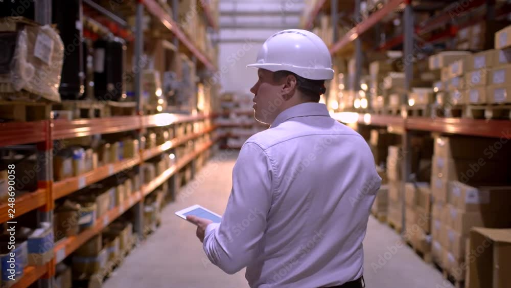 employee male warehouse worker engineer man in hard hat working at construction site warehouse, walking in logistics center factory. engineer using tablet computer, architect businessman man indoors employee male warehouse worker engineer man in hard hat working at construction site warehouse, walking in logistics center factory. engineer using tablet computer, architect businessman man indoors