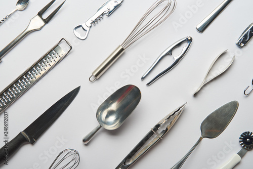 flat lay with shiny metal cooking utensils on grey background