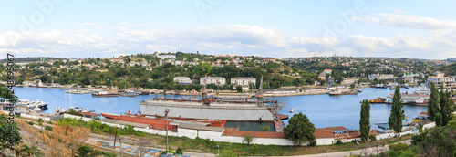 Panorama of Yuzhnaya bay in Sevastopol, Ships of the Black Sea Fleet of Russia and view to the factory and the city. photo