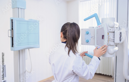 back view  picture of a female radiologist adjusting the X-ray machine in examination rom