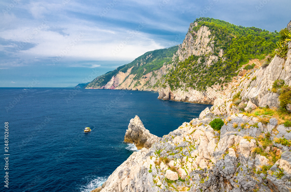 Grotta di Lord Byron with blue water, coast with rock cliff, yellow boat and blue sky near Portovenere town, Ligurian sea, Riviera di Levante, National park Cinque Terre, La Spezia, Liguria, Italy
