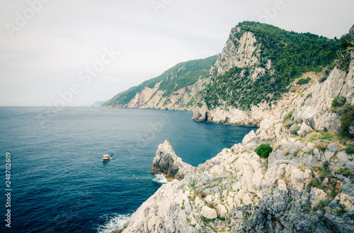 Grotta di Lord Byron with blue water, coast with rock cliff, yellow boat and blue sky near Portovenere town, Ligurian sea, Riviera di Levante, National park Cinque Terre, La Spezia, Liguria, Italy