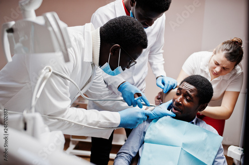 Multiracial dentist doctors team. African american man patient preparing for surgery.