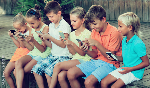 Group of kids playing with mobile phones outdoors