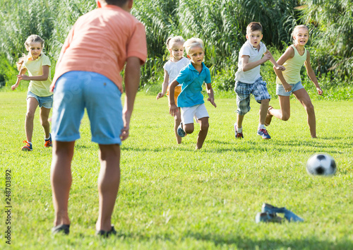 kids kicking football in park
