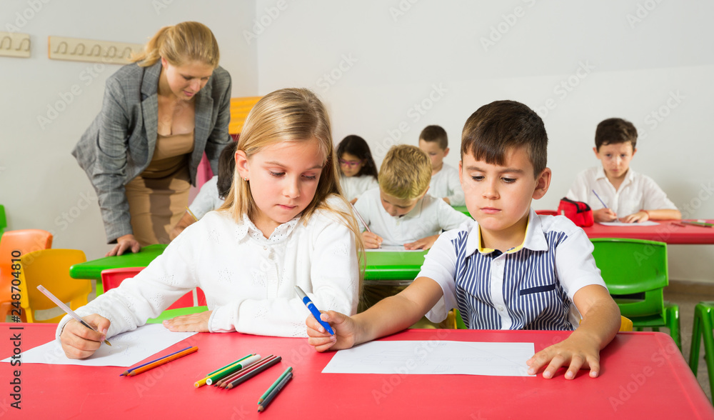Fototapeta premium Portrait of schoolgirl and schoolboy at desk
