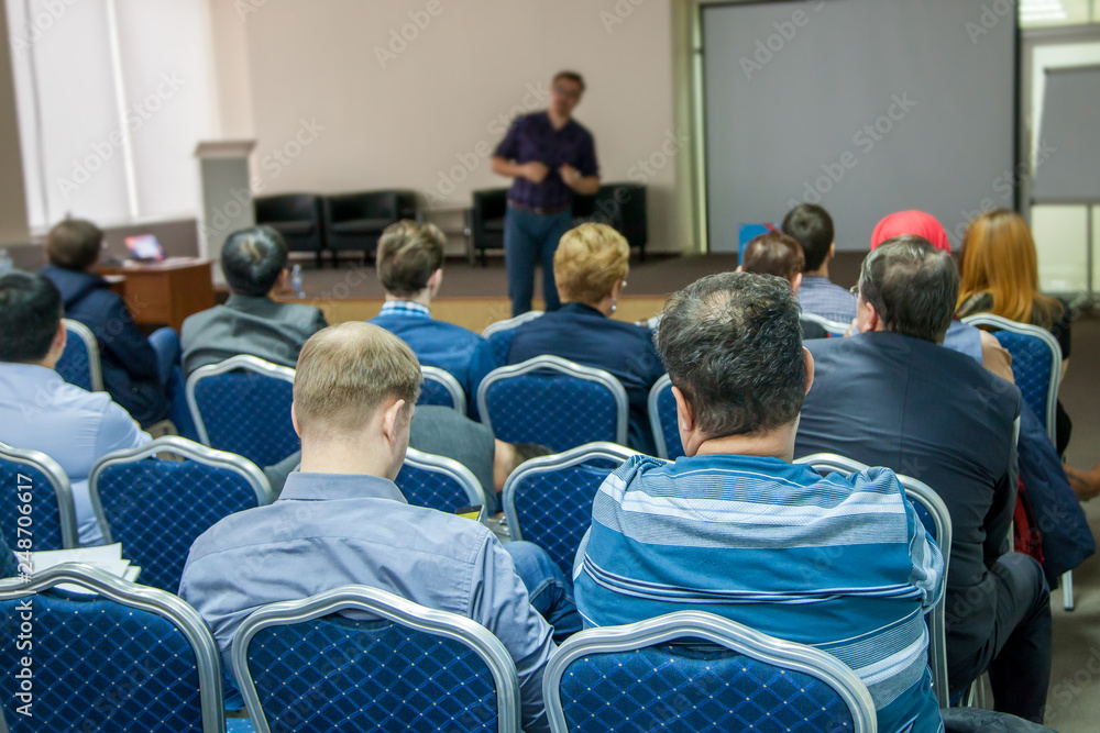 The speaker makes a report at a business meeting. Spectators in the conference room. Business and entrepreneurship.