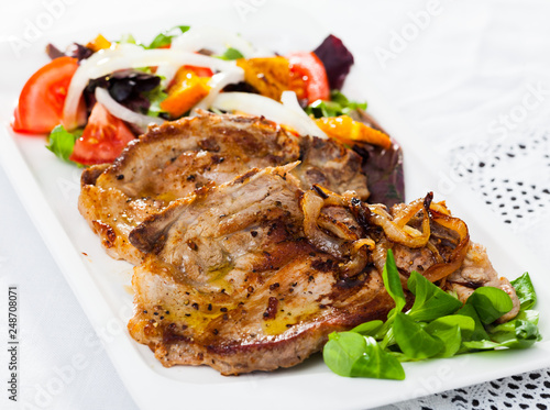 Fried pork meat chops with salad of fried orange and vegetables