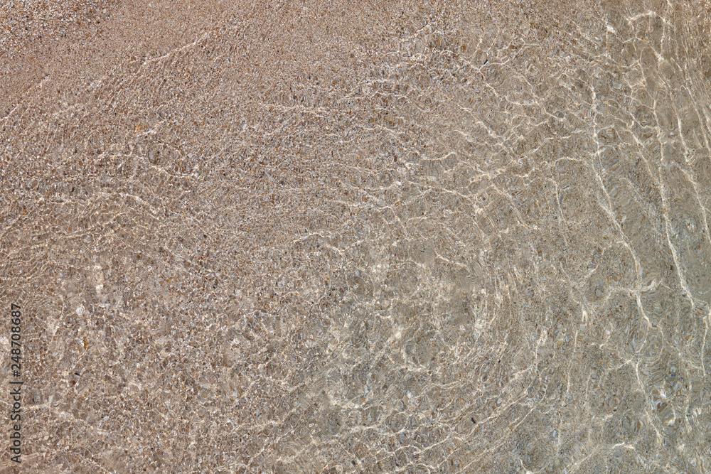 Sunbeams in shallow water. Abstract seashore background.