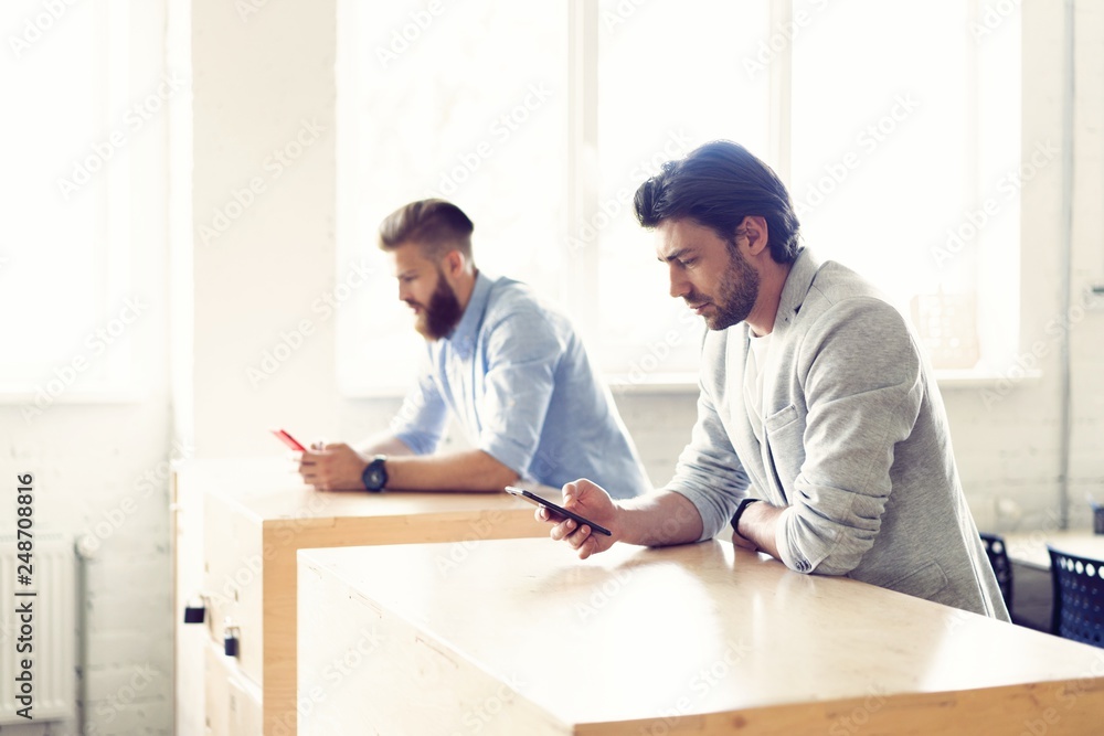 Two young professionals looking at a smartphone. Two young professionals looking at a smartphone.