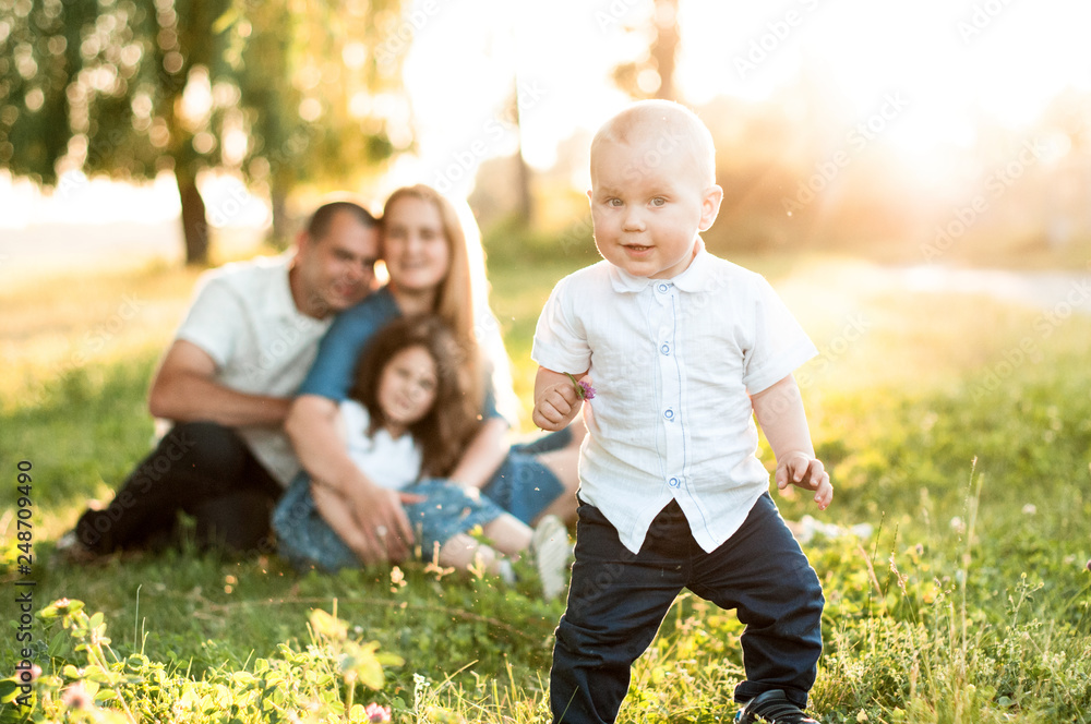 baby in the sunset sun on the background of his family in the park baby in the sunset sun on the background of his family in the park