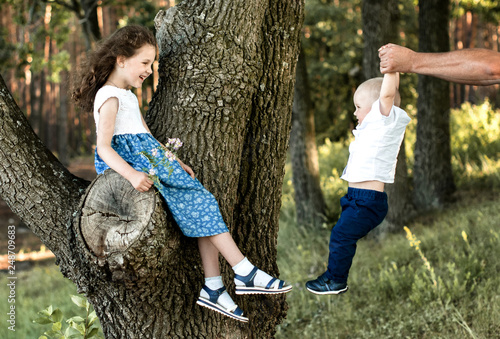 children having fun in the forest. Older sister teasing with younger brother photo