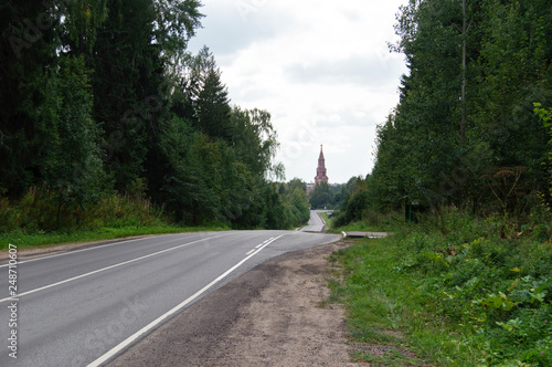 Empty road to the tower with the forest at the sides photo