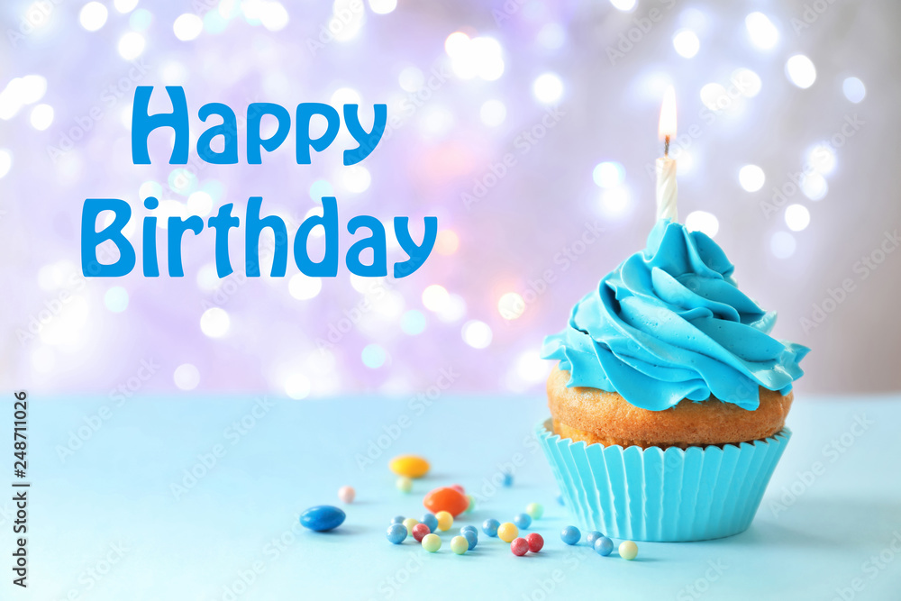 Delicious birthday cupcake with candle on table against blurred background Delicious birthday cupcake with candle on table against blurred background