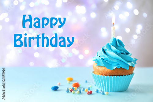 Delicious birthday cupcake with candle on table against blurred background