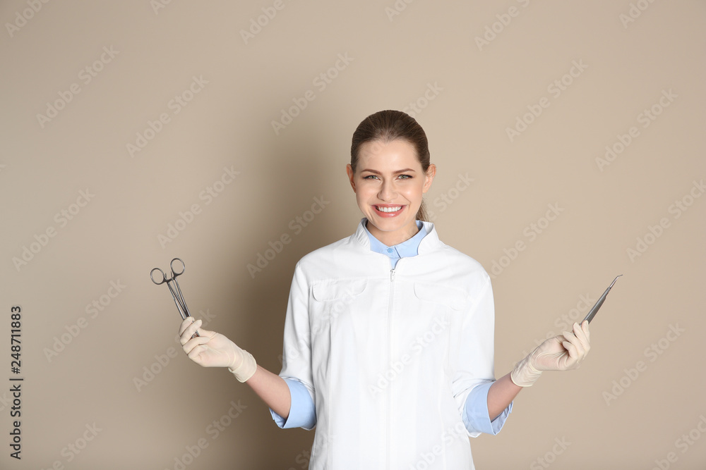 Female dentist holding professional tools on color background