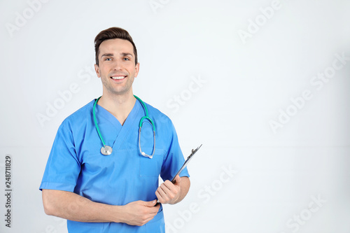 Portrait of medical assistant with stethoscope and clipboard on light background. Space for text