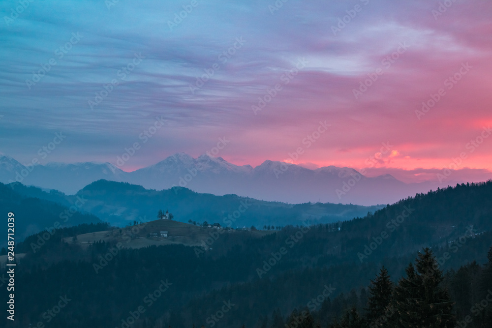View of the alps in the morning with the st. Tomaz church on the top of the hill, Slovenia