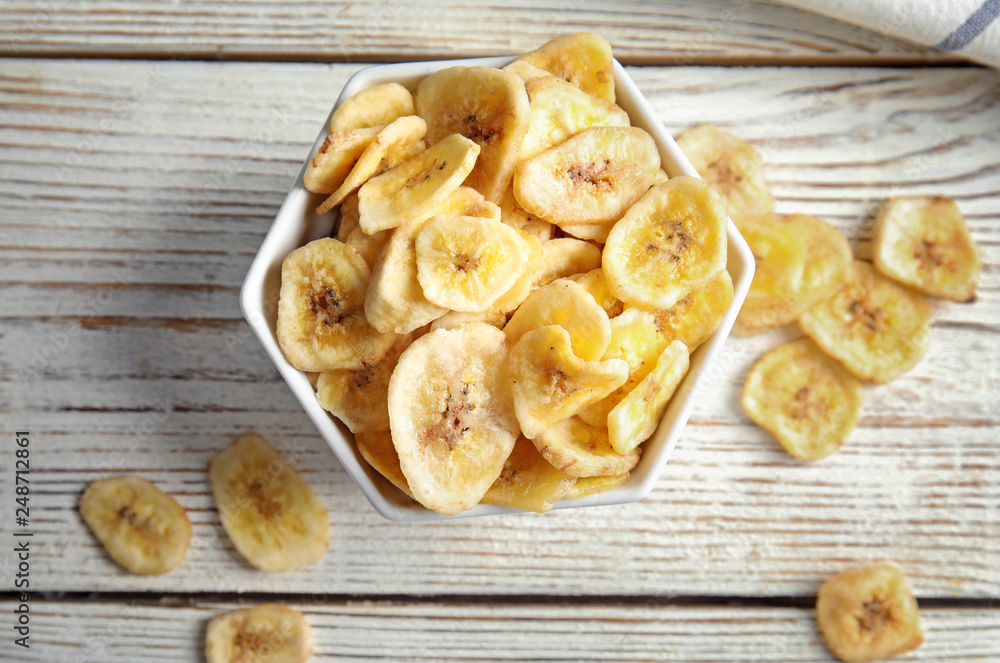 Bowl with sweet banana slices on wooden table, top view. Dried fruit as healthy snack Bowl with sweet banana slices on wooden table, top view. Dried fruit as healthy snack