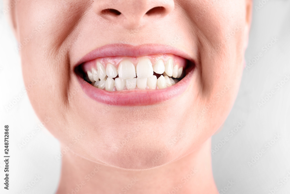 Obraz premium Young woman with healthy teeth smiling on white background, closeup