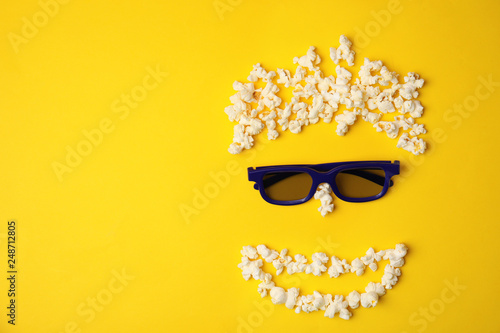 Face made of popcorn and glasses on color background, top view with space for text. Cinema snack