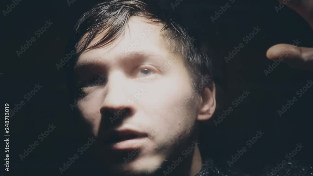 The guy under the influence of drugs trying to see something through the glass The guy under the influence of drugs trying to see something through the glass