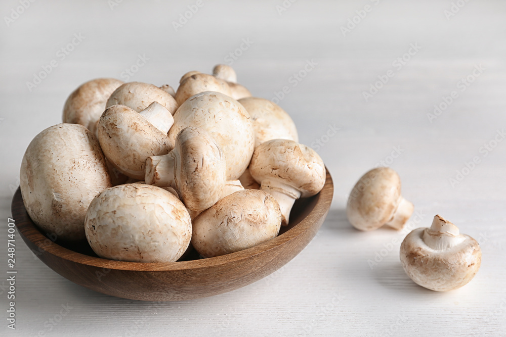 Bowl with fresh champignon mushrooms on wooden table. Space for text Bowl with fresh champignon mushrooms on wooden table. Space for text