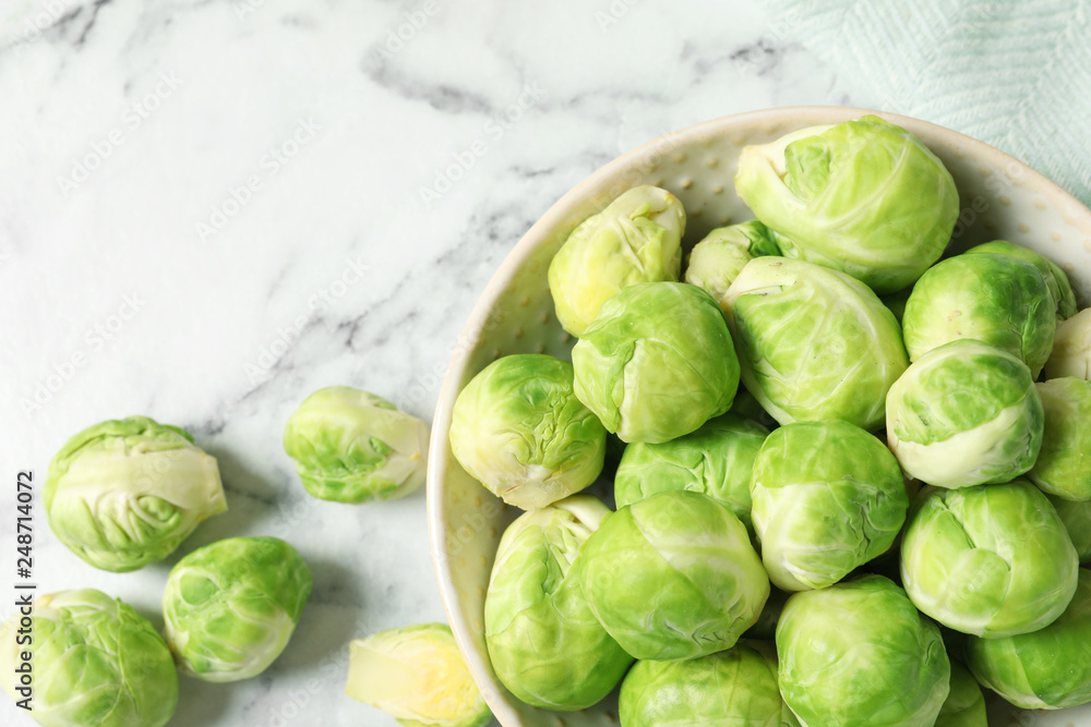 Bowl with fresh Brussels sprouts on marble table, top view. Space for text Bowl with fresh Brussels sprouts on marble table, top view. Space for text