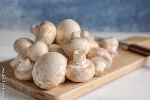 Fresh champignon mushrooms on wooden board, closeup