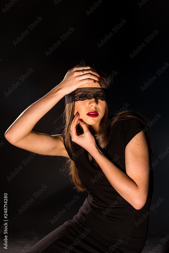 Portrait of a beautiful young woman in a black dress with a cool makeup and good skin. Studio, black background.