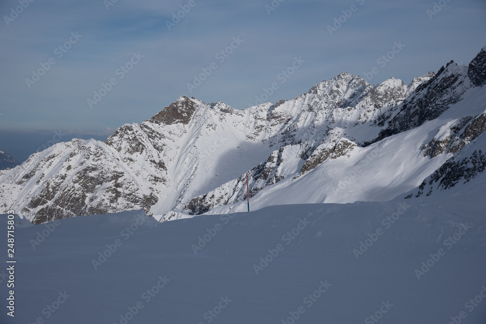 Fototapeta premium View of the Presena glacier at 3100 meters of altitude and the mountains around the Tonale Pass, during a winter sunny day. Tonale is a mountain pass between Lombardy and Trentino