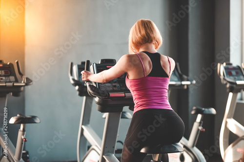 The girl is engaged on a stationary bike. Beautiful woman on exercise bike. Girl in gym 
