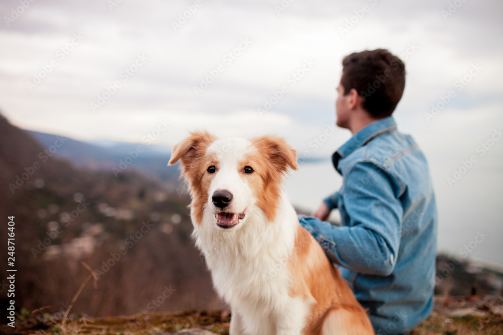 Man sit with his dog in the mountains and look forward Man sit with his dog in the mountains and look forward