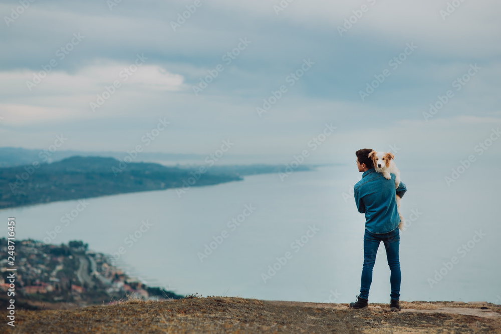 Man stay with his dog in the mountains and look forward