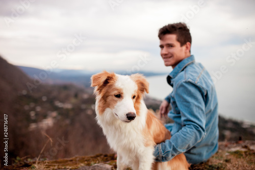 Man sit with his dog in the mountains and look forward © Kseniya