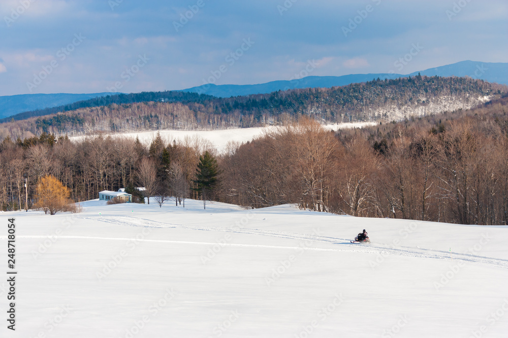 Snowmobile running along a trail in a wide open scenic, Morrisville, Vermont, USA Snowmobile running along a trail in a wide open scenic, Morrisville, Vermont, USA