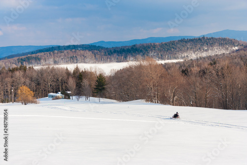Snowmobile running along a trail in a wide open scenic, Morrisville, Vermont, USA photo