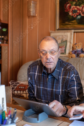 Focused senior man using tablet at home